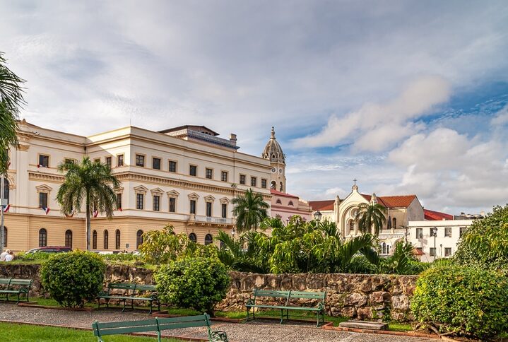 Panama City, Panama - November 30, 2008:  Large government building and tower and entrance of Sanctuario de la Esperanza part of San Francisco de Asis church under cloudscape. Simon Bolivar Square.