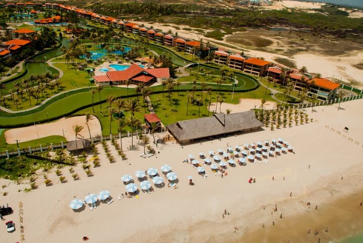 "This is an aerial shot of Canoa Quebrada beach, with a great view of the repetative patterns that are created by the large umbrellas on the beach, palm trees and the hotel resorts."