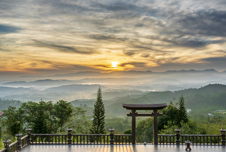 Dawn in front of temple gate with impressive colorful clouds in sky shines under mist valley