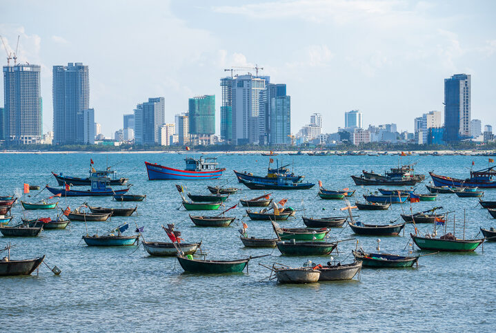 Danang, Vietnam - june 06, 2020 : Traditional Vietnamese fishing boats on open sea on the background of high-rise buildings of the city Danang, Vietnam