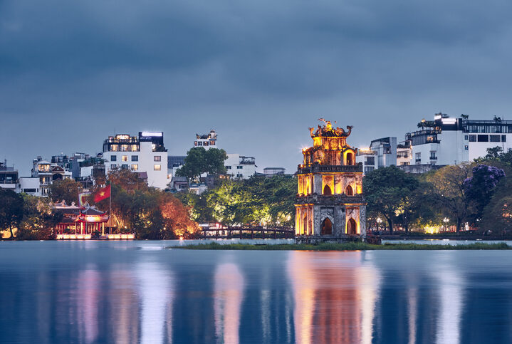 Skyline of Hanoi at dusk. Turtle Tower on Hoan Kiem Lake in old quarter.